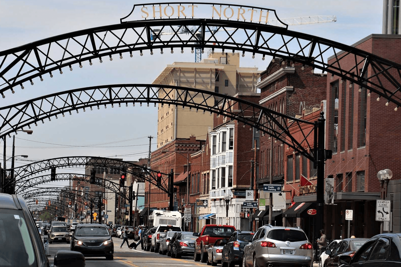 A busy street in the Short North district featuring traffic and historic storefronts under an archway.
