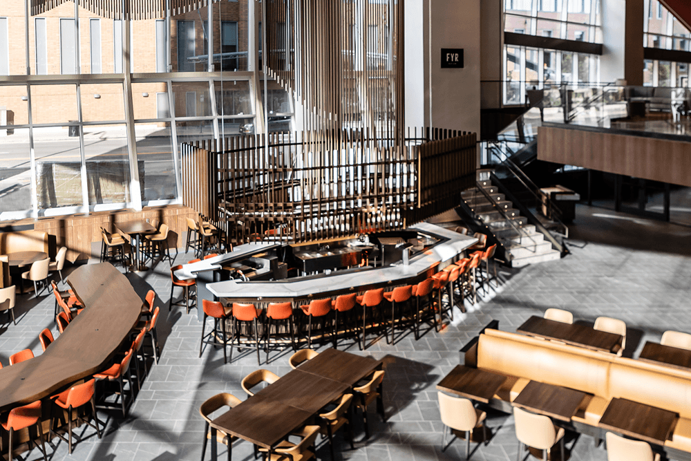 A modern restaurant interior featuring various seating arrangements and a central bar area.